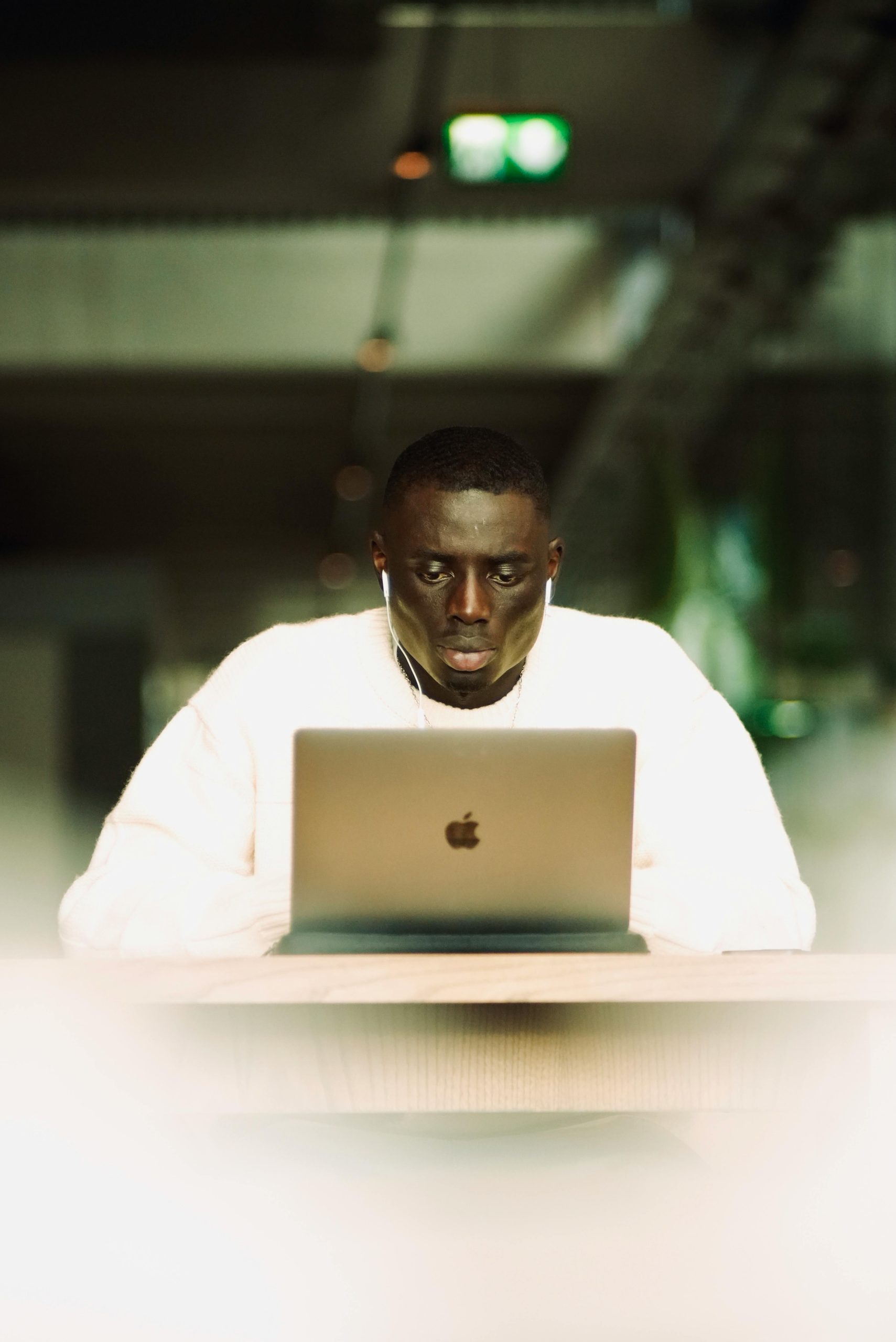 A man intensely focused on work using his laptop indoors with earphones on.