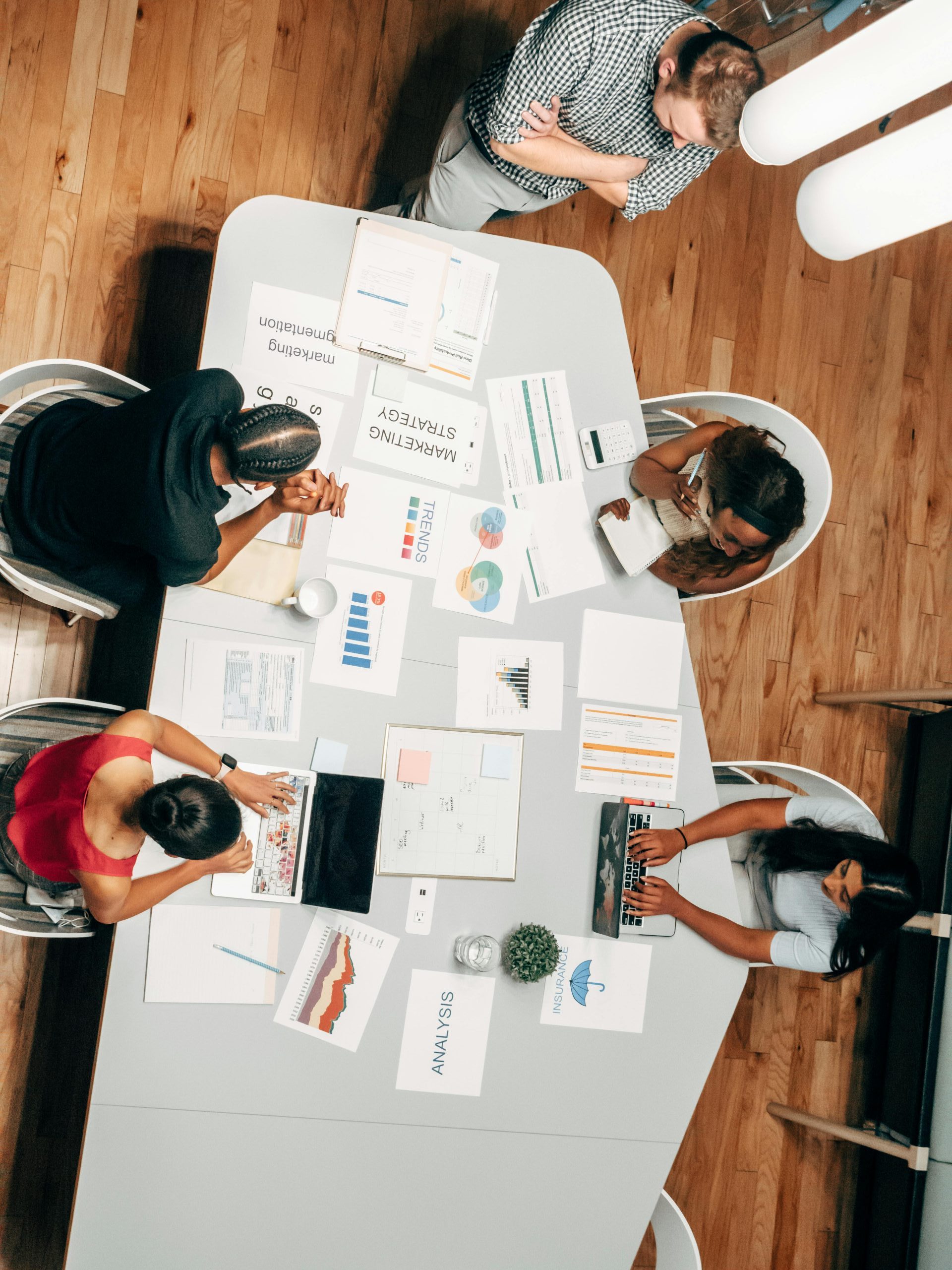 A diverse group working on marketing strategies with charts and laptops in an office setting.